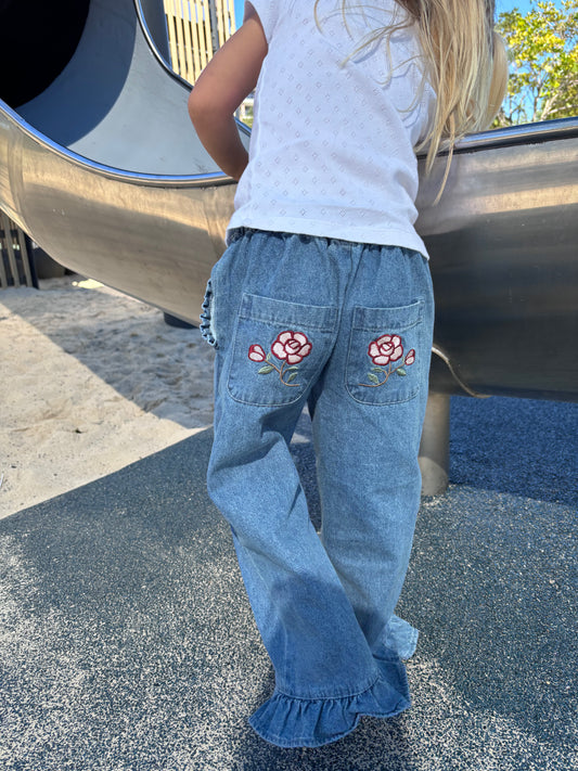Child at a playground slide in the Don Rose Pant, rose back pockets and ruffle hem showing