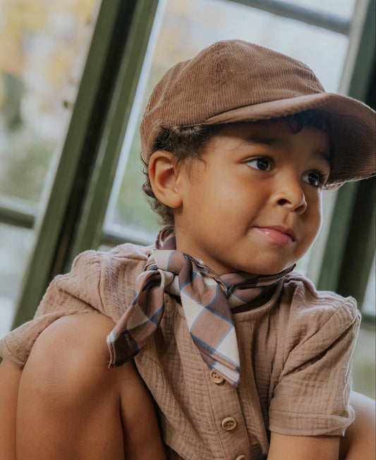 Child in the Pine Bark short set with a brown cap and checked neckerchief