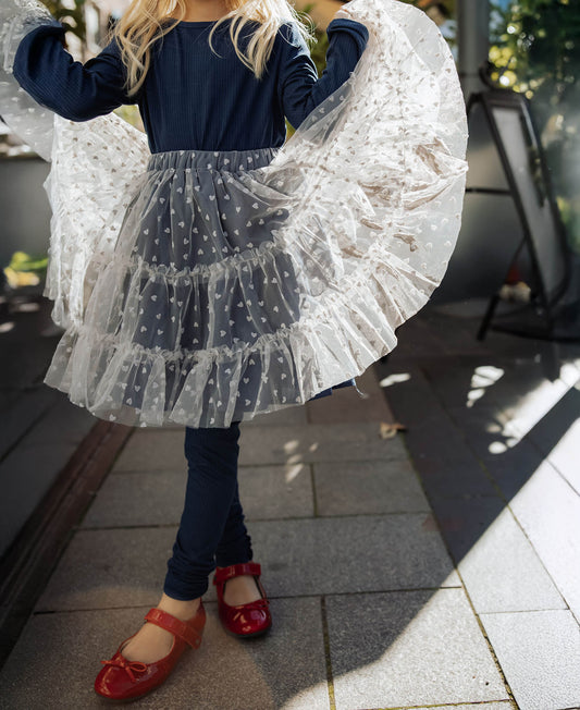 Child twirling in the Slate Tulle Skirt with navy tights and red shoes, seen from behind