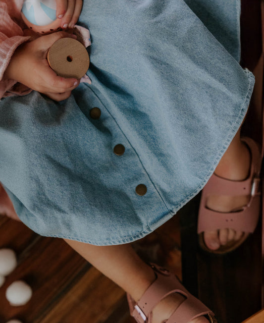Close-up of the light denim button-front skirt, child in pink sandals