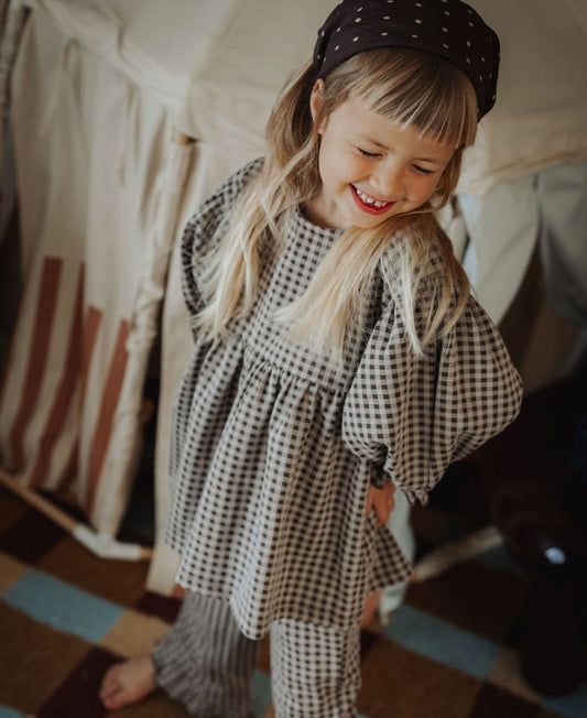 Smiling child in the gingham Ella Blouse and matching pants