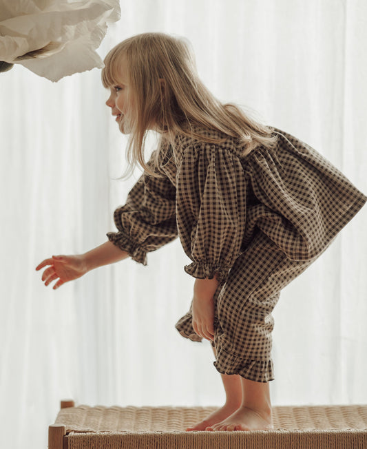 Child climbing onto a bench in the matching brown gingham Ella Blouse and Ella Pant