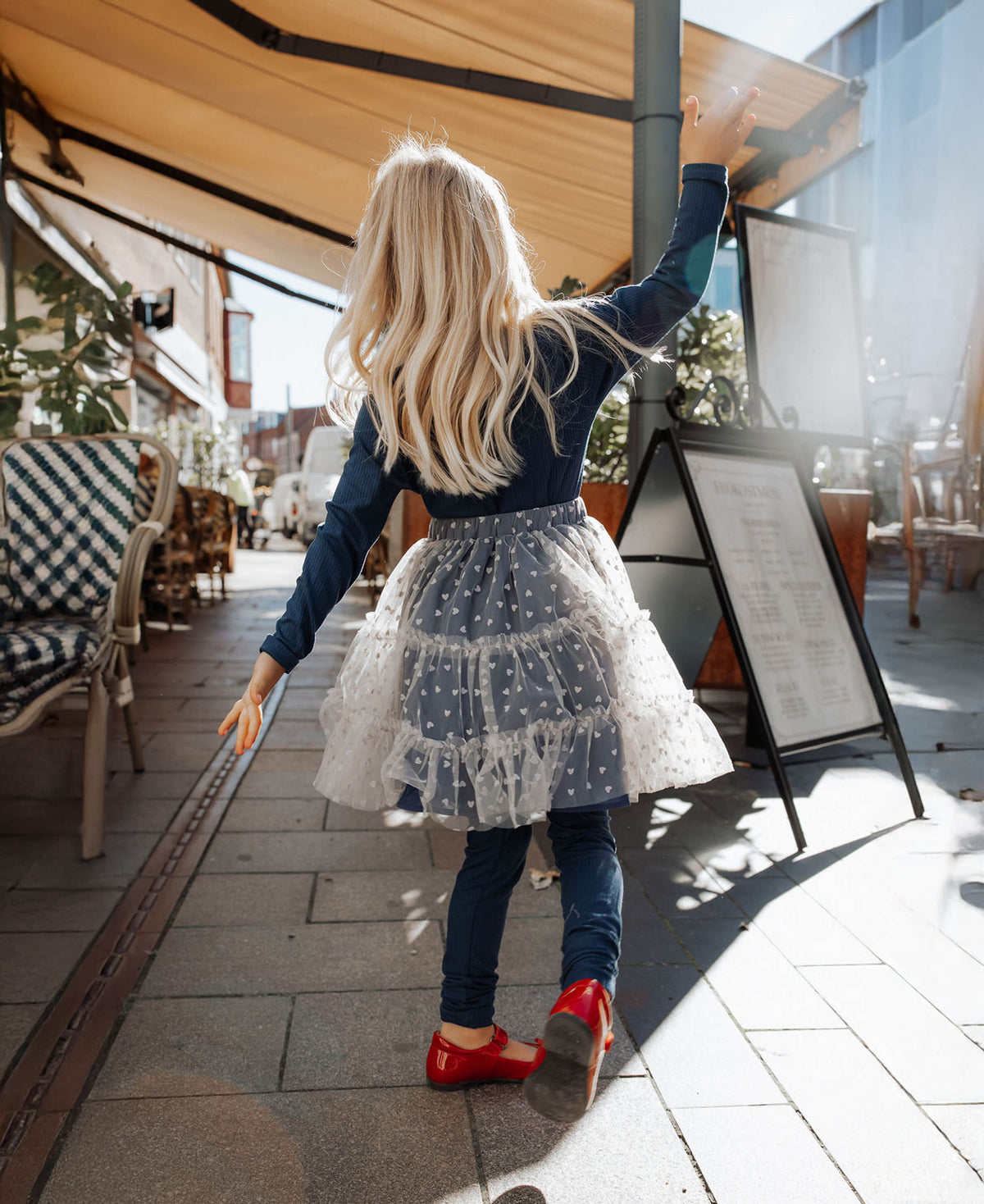 Child walking down a café street in the Slate Tulle Skirt and red Mary Janes