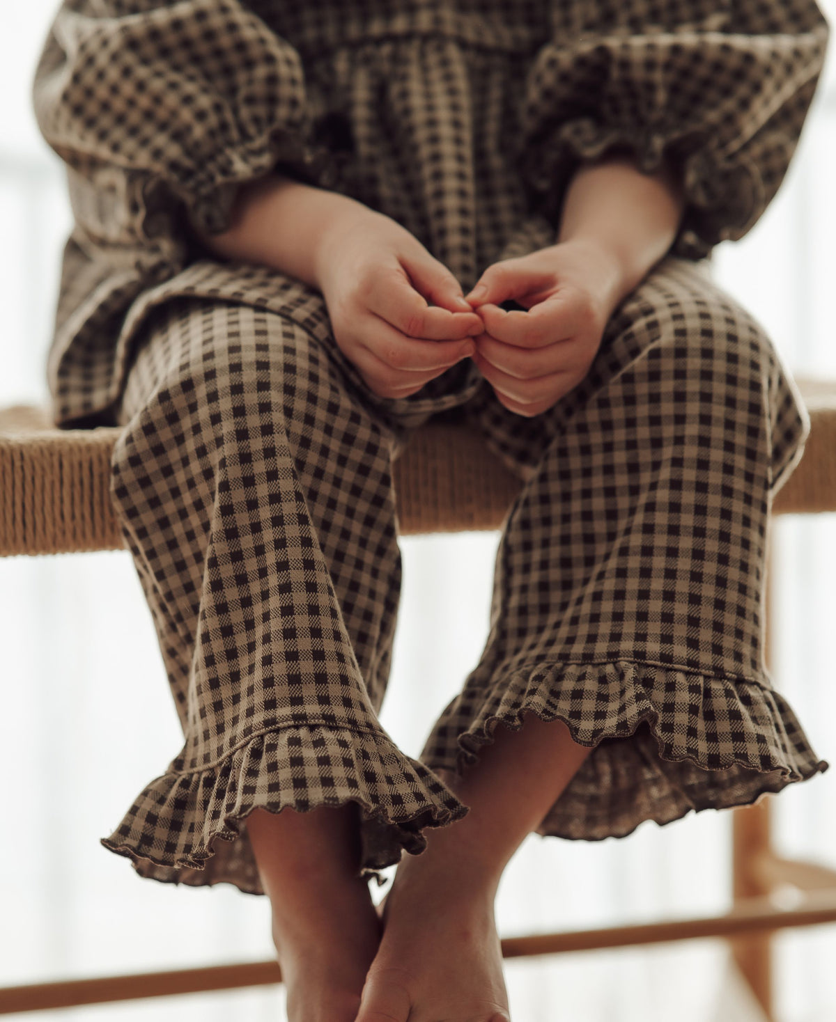 Close-up of the Ella Pant ruffle hems, child sitting barefoot