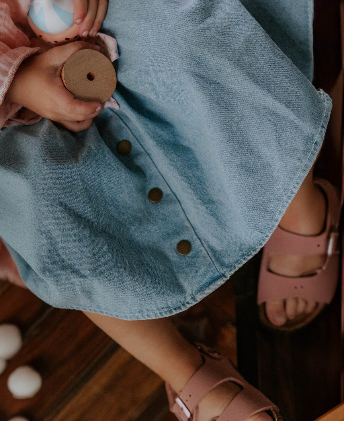 Close-up of the light denim button-front skirt, child in pink sandals