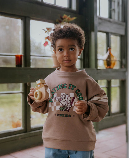 Child in the brown Alvin Cool Sweatshirt holding a toy camera