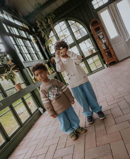 Two children in a tiled conservatory, one in the Alvin Cool Sweatshirt