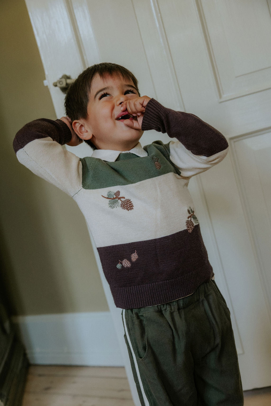 Child wearing the Fliink Donny Pant in beetle green with cream side stripes, styled with a knit jumper