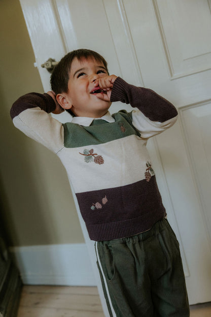 Child wearing the Fliink Donny Pant in beetle green with cream side stripes, styled with a knit jumper
