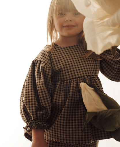 Child in the brown gingham Ella Blouse holding a soft toy