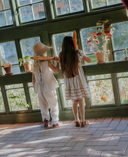 Two children at a conservatory window, one in the Bridget Top, seen from behind
