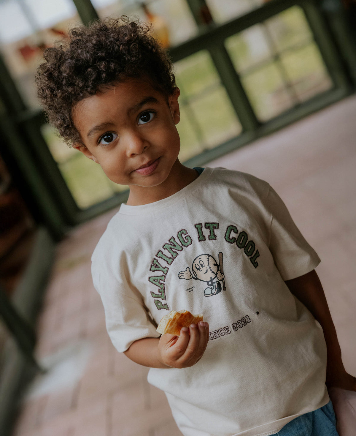 Child in the cream Sommer Cool T-shirt holding a biscuit