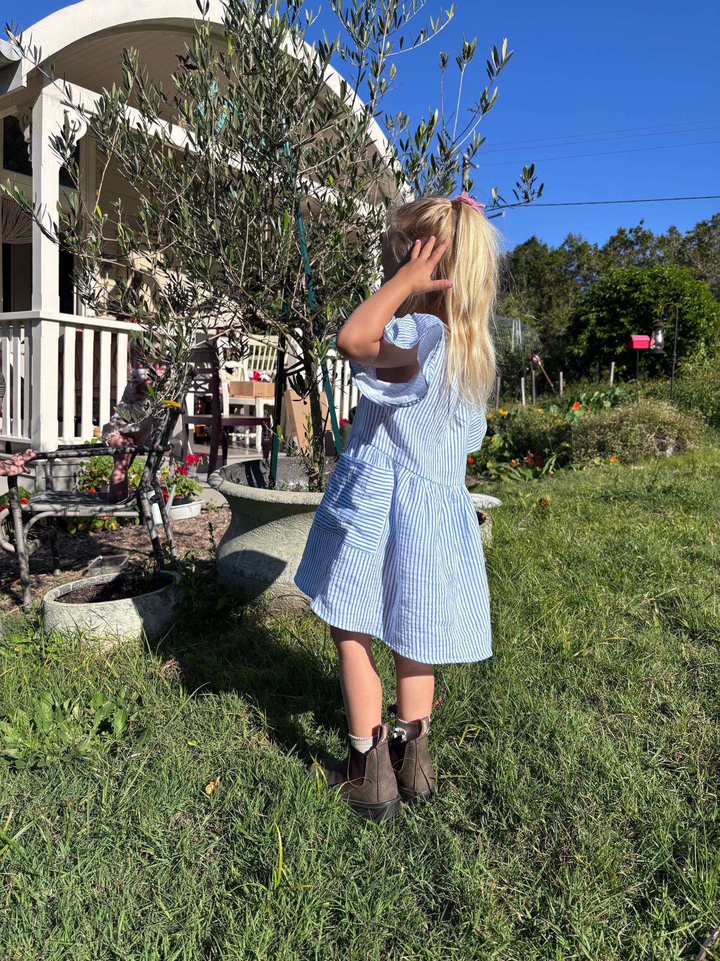 Child in the Cha Cha Dress in a backyard garden, looking away