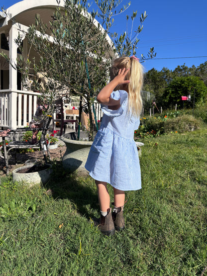 Child in the Cha Cha Dress in a backyard garden, looking away
